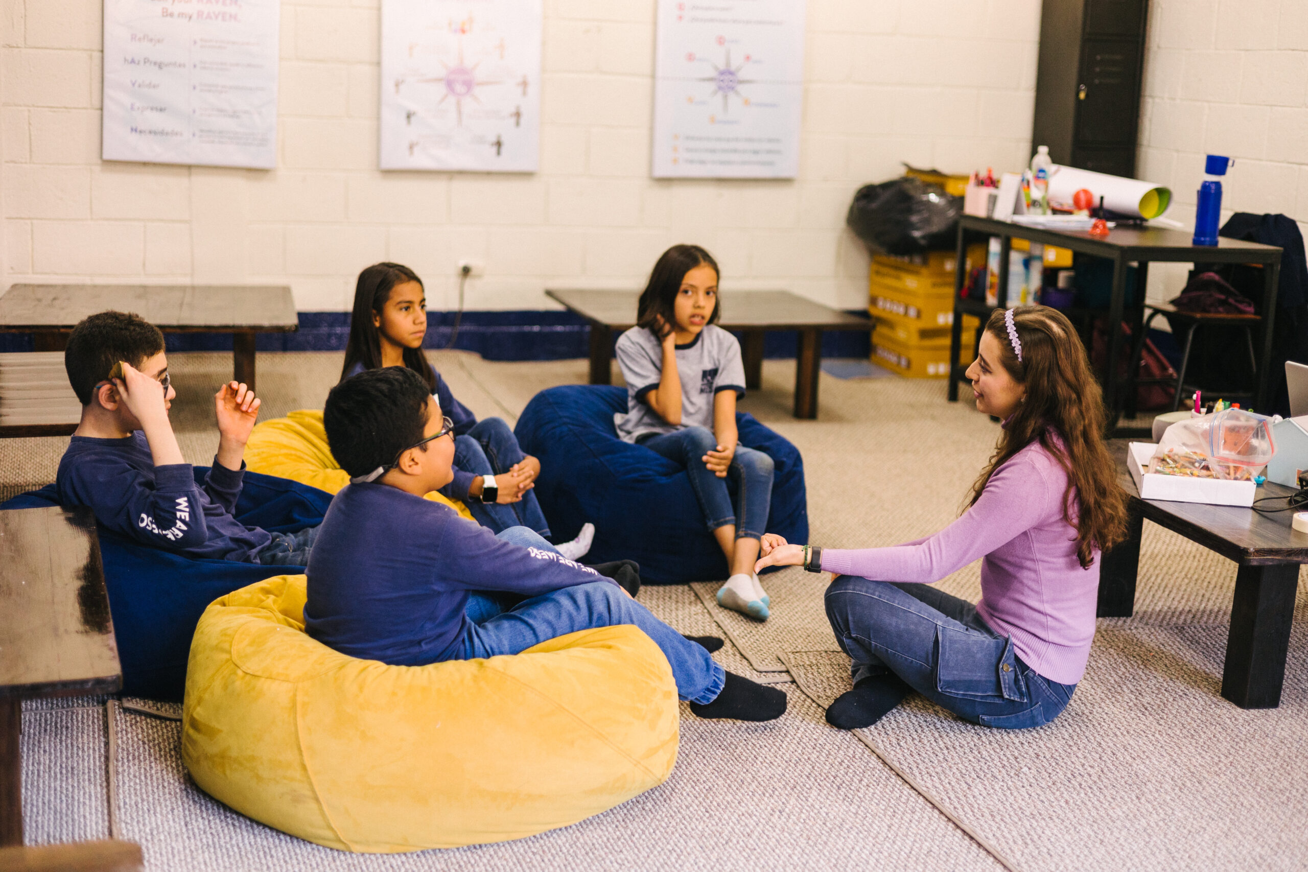 Teacher talking to kids sitting in bean bags listening to her. 